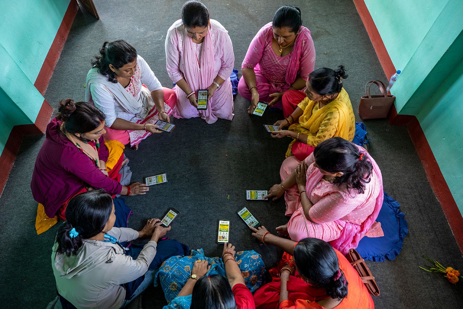 An overhead shot of a group of women sitting in a tight circle and holding out their cellphones.